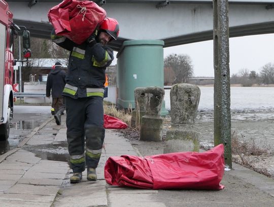 Strażacy rozstawiają rękawy przeciwpowodziowe na Bulwarze Zygmunta Augusta
